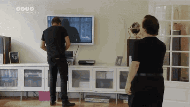two men are standing in front of a flat screen tv which says sonic dynamite 2 on it
