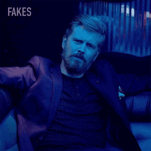 a man in a suit is sitting on a couch with fakes written on the bottom