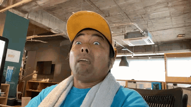 a man wearing a yellow hat and a blue shirt looks surprised