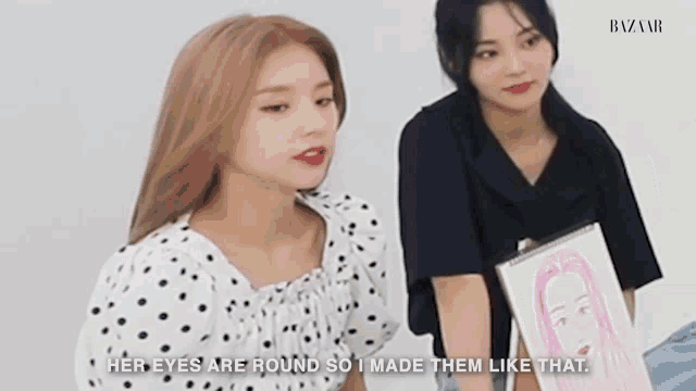 two women are sitting next to each other and one is holding a drawing of a woman .
