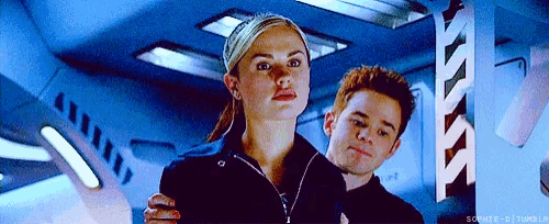 a man and a woman are standing next to each other in a room . the woman is wearing a headband .
