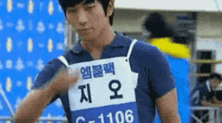 a man wearing a blue shirt with a white tag that says c-1106 on it