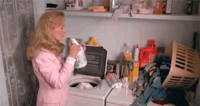 a woman in a pink jacket is standing in front of a washing machine in a laundry room .