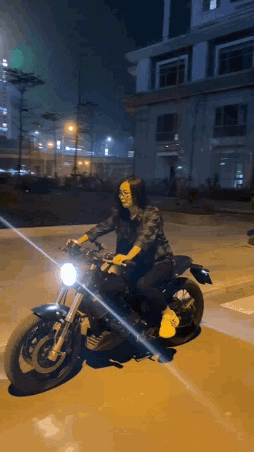 a woman is riding a motorcycle at night with a yellow light shining on her