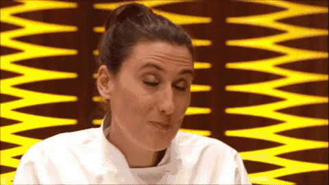 a woman in a chef 's uniform is making a face in front of a yellow background