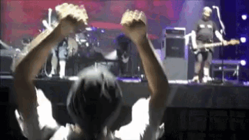 a man playing a guitar in front of a crowd with their arms in the air