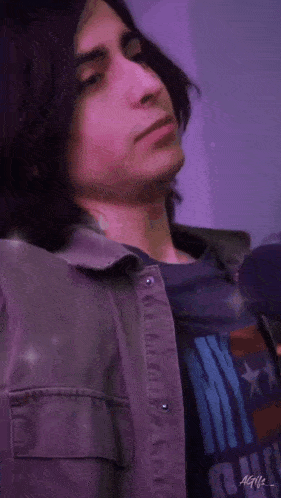 a young man with long dark hair is wearing a purple shirt and a purple jacket