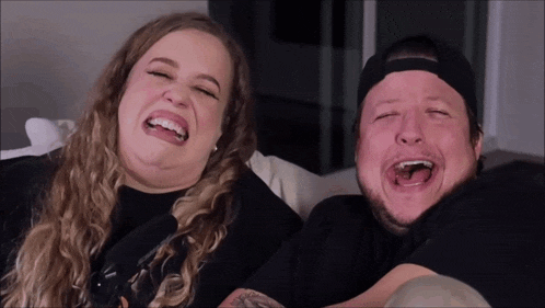 a man and a woman are sitting on a couch laughing