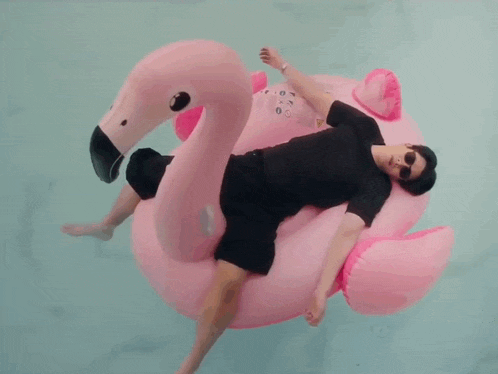 a man is laying on a pink flamingo float in the water