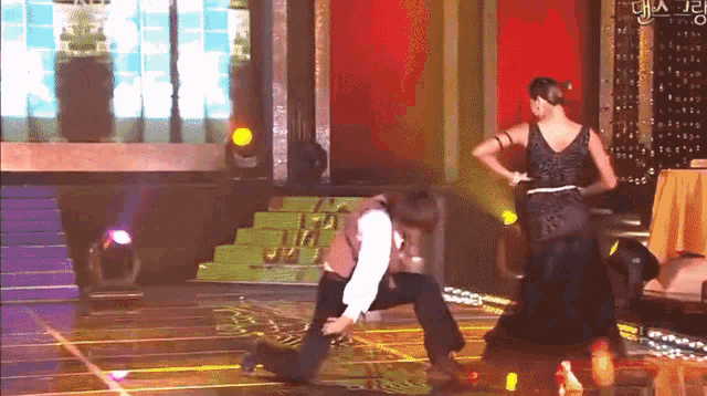 a woman in a black dress is dancing with a man on a stage