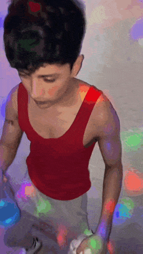 a man in a red tank top is standing in front of a colorful background ..
