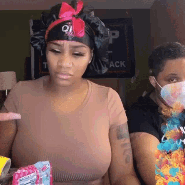 a woman wearing a headband and a mask is standing next to another woman wearing a mask .