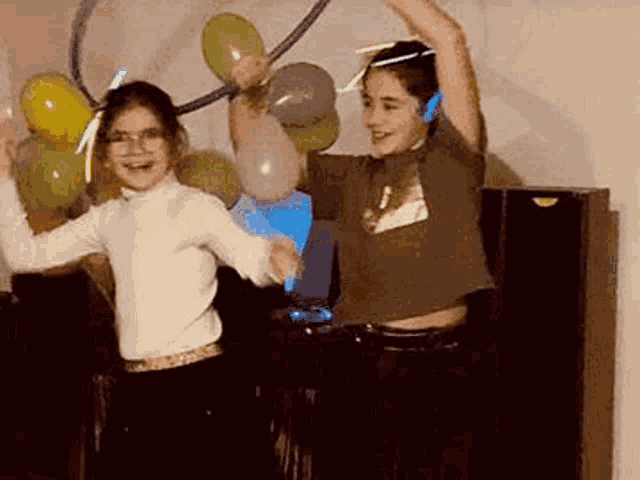 a boy and a girl are dancing in a dark room with balloons and glow in the dark headphones .