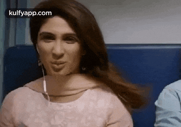 a woman is sitting on a train with her hair blowing in the wind and wearing earphones .
