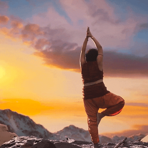 a person is doing a yoga pose in front of a mountain at sunset