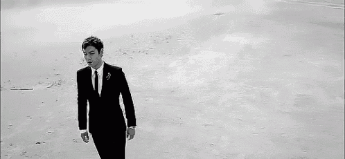 a man in a suit and tie is walking on a beach