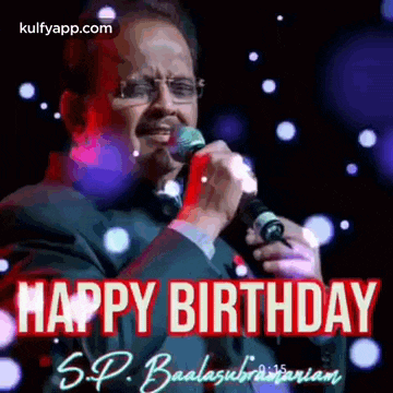 a man is singing into a microphone with the words `` happy birthday '' written on it .