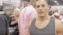 a man in a gray tank top stands in a crowd of people