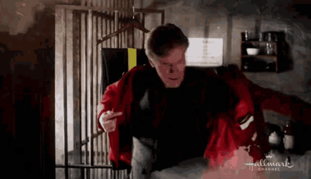 a man in a red jacket is standing in a hallway with a sign that says hallmark channel