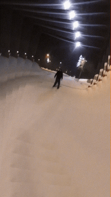 a person is skiing down a snow covered slope at night