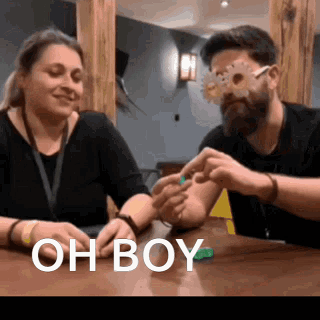 a man and a woman are sitting at a table with the words oh boy written on the table