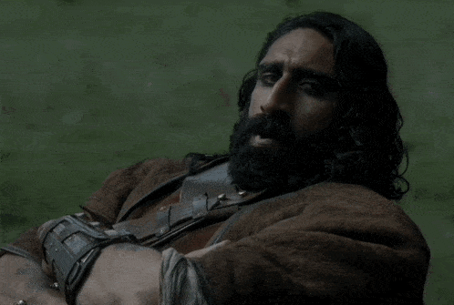 a man with long hair and a beard is wearing a wristband