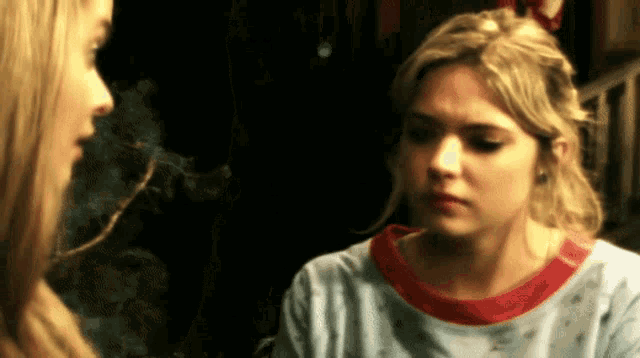 a woman smoking a cigarette while another woman looks at her