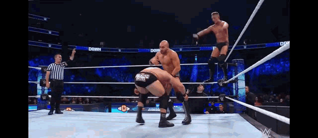 two men are wrestling in a wrestling ring with a referee watching .