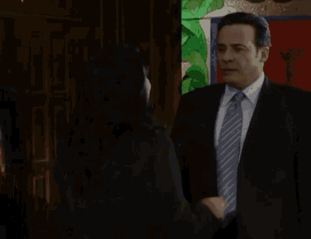 a man in a suit and tie is hugged by a woman