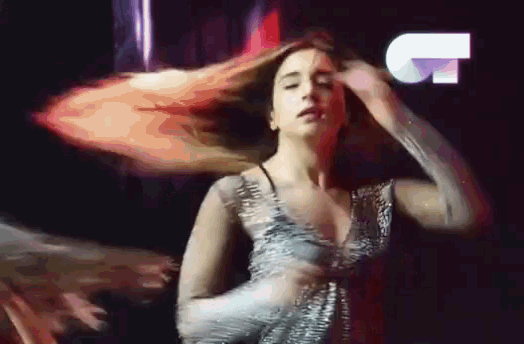a woman in a dress is dancing in front of a sign that says ' t ' on it .