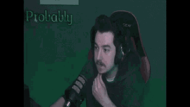 a man is making a stop sign in front of a microphone on a green screen .