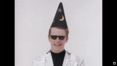 a man is wearing a wizard hat and sunglasses and smiling .