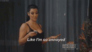 a woman in a black tank top is holding a cell phone and says like i 'm so annoyed