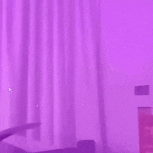 a man is pouring a drink into a glass in front of a purple background .