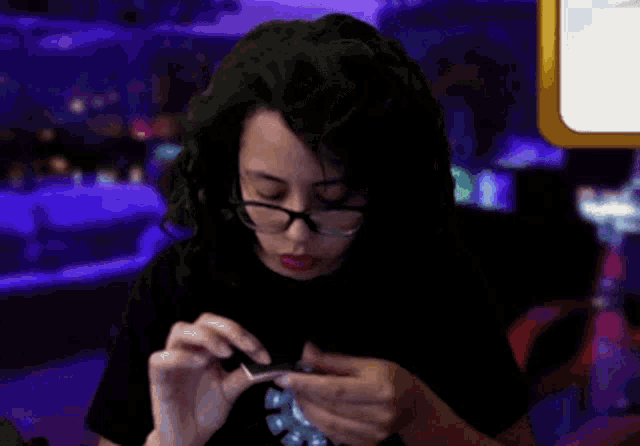 a woman wearing glasses and a black shirt is smiling while playing a game