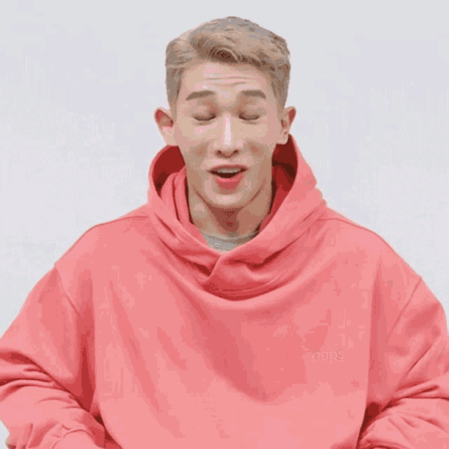 a man wearing a pink hoodie with the word naps on the front
