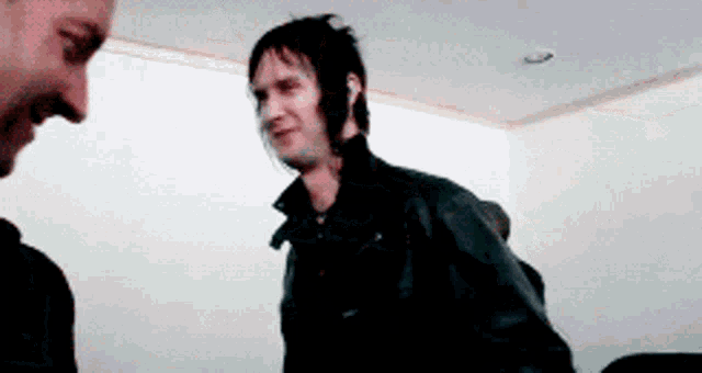 a man in a black jacket is talking to another man in a black jacket