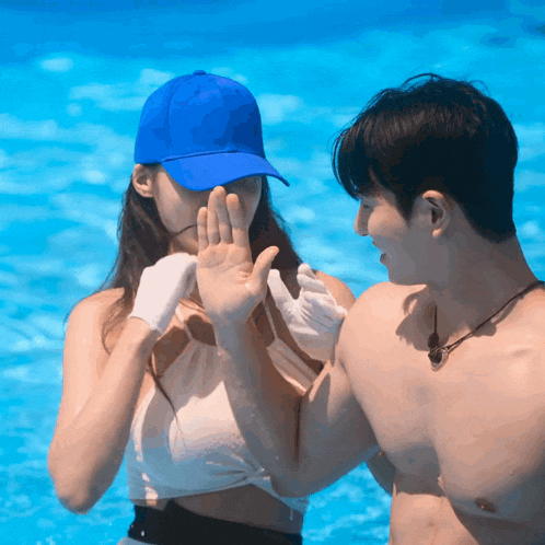 a man and a woman are standing in a pool and the woman is wearing a blue hat and gloves