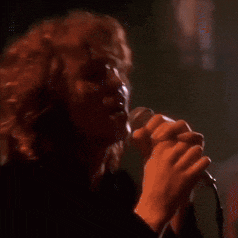 a close up of a person singing into a microphone in a dark room