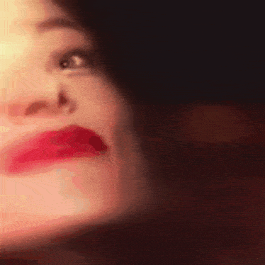 a close up of a woman 's face with her eyes closed and red lips .