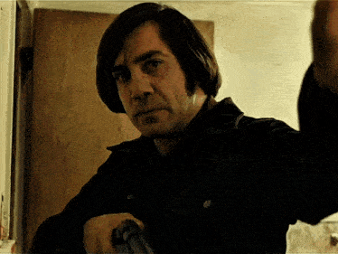 a man in a black jacket is holding a gun in his hand