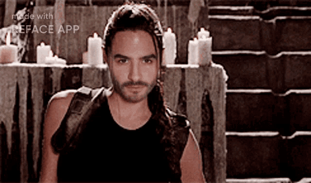 a man with long hair and a beard is standing in front of candles