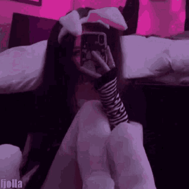 a girl with bunny ears is taking a selfie with her phone .