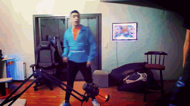 a man in a blue shirt is standing in a room with a picture on the wall