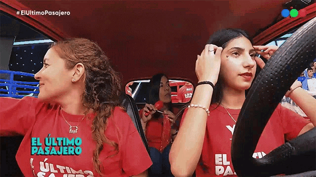three women wearing red shirts that say el ultimo pasajero are sitting in a car