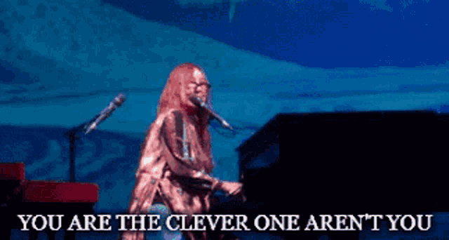 a woman singing into a microphone with the words you are the clever one aren 't you below her