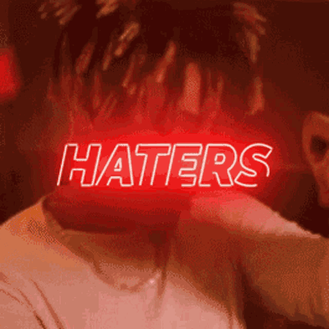 a man 's face is lit up with the word haters