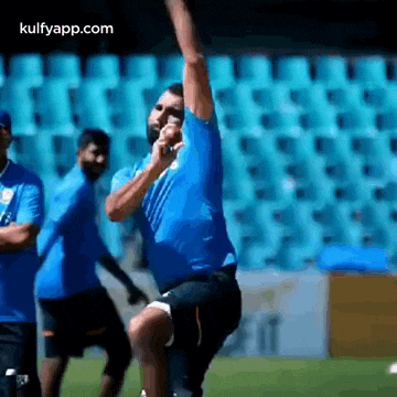 a man in a blue shirt is throwing a ball on a soccer field .