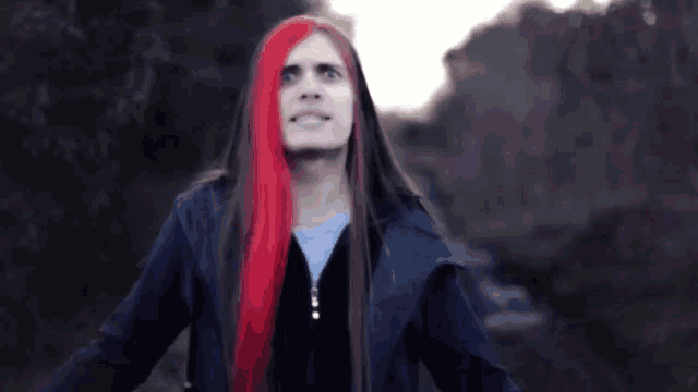 a man with long red hair is wearing a black jacket and a hood .