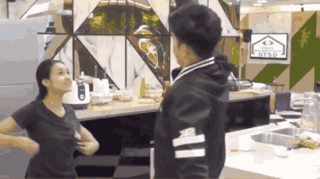a man and a woman are standing in a kitchen with a sign that says pinoy celebrity otso